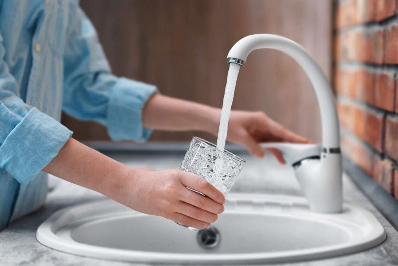 жінка набирає воду з раковини