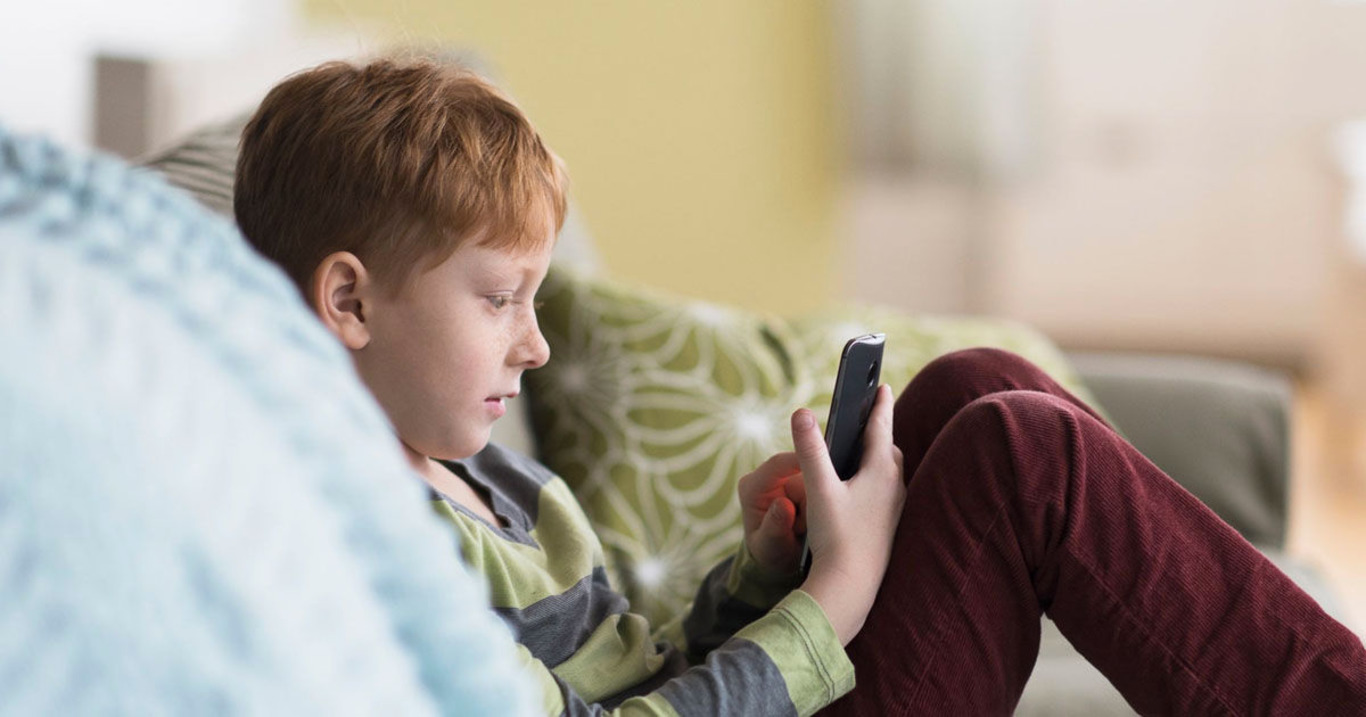 підліток грає у телефоні