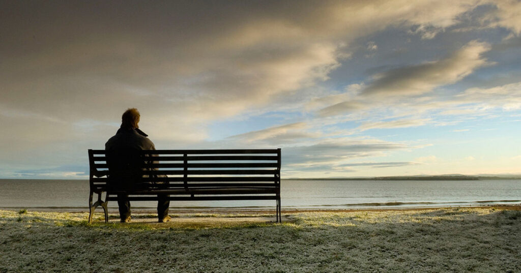 чоловік сидіть на скамійці