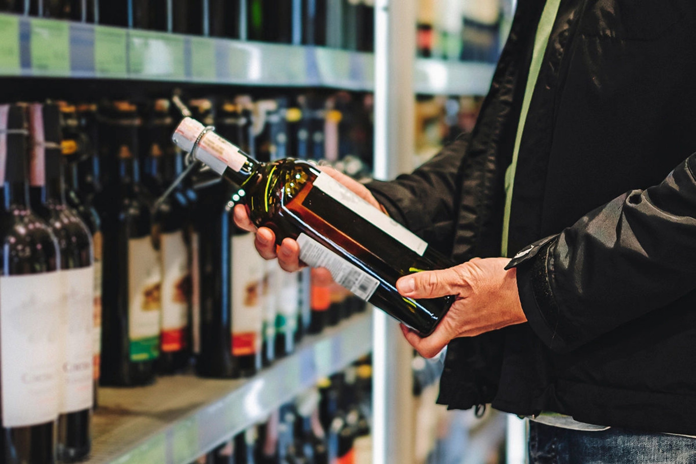 людина із пляшкою вина у супермаркеті